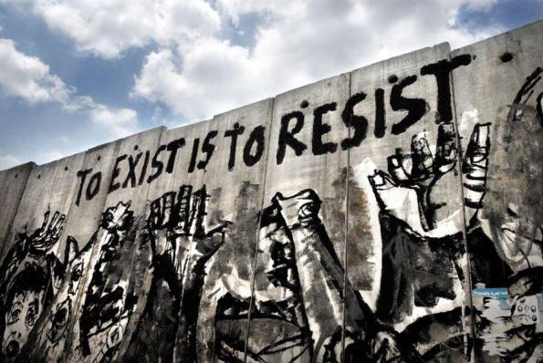 The apartheid wall art "To exist is to resist" reads in bold red letters 