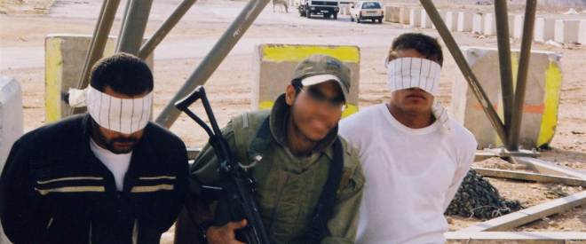 An Israeli soldier poses with Palestinian detainees in an undated photo taken by an Israeli soldier and made available by the campaign group Breaking the Silence.